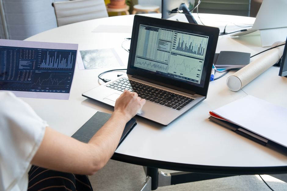 Decisões da Presidência — Business person evaluating financial charts on a laptop in a modern office setting.